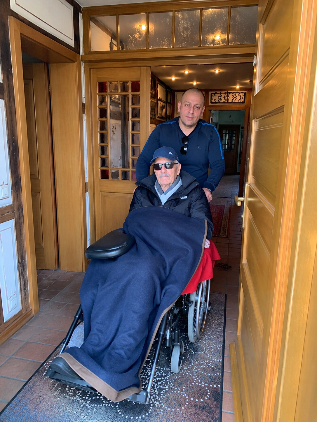 Stefan begleitet einen älteren Menschen im Rollstuhl